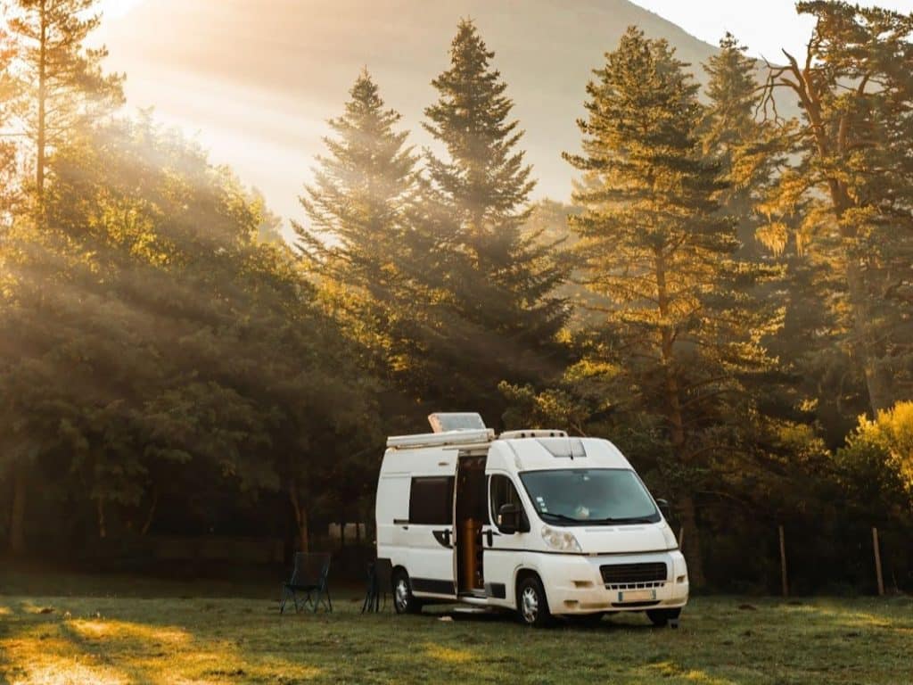 White panel van camper parked at sunrise in the mountains, illustrating off-grid campervan travel in retirement.