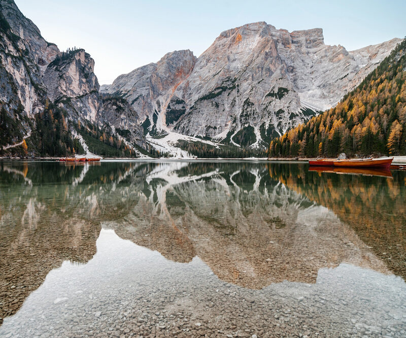 campervan travelling through alpine mountains beside a reflective lake in Europe