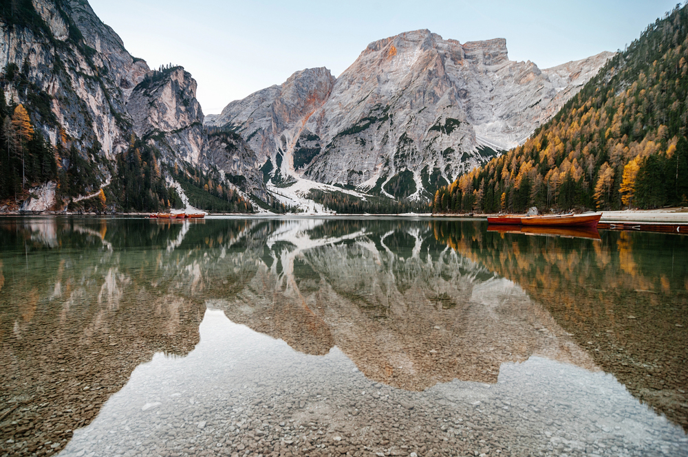 campervan travelling through alpine mountains beside a reflective lake in Europe