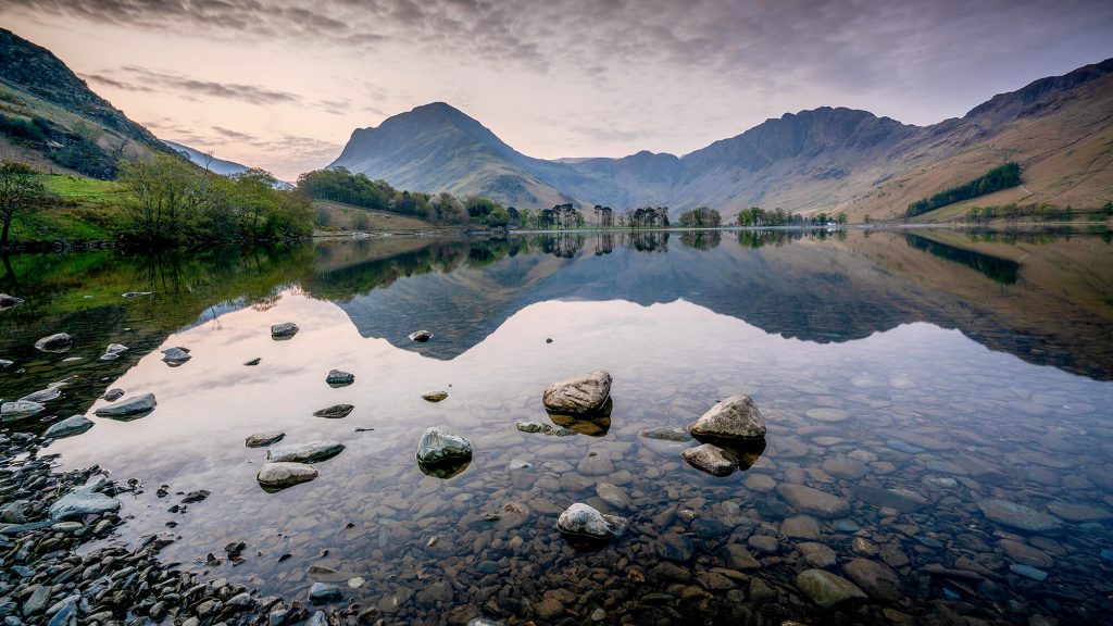 Peaceful lakeside landscape with still water and surrounding hills, ideal setting for a campervan stop.