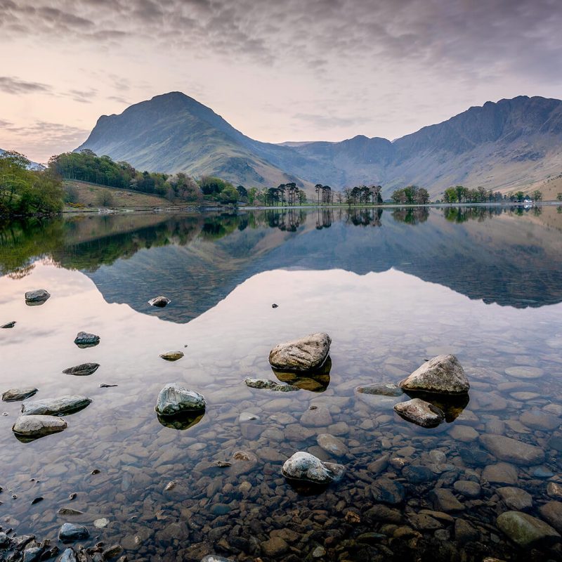 Peaceful lakeside landscape with still water and surrounding hills, ideal setting for a campervan stop.