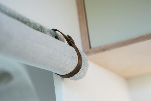 Campervan grab handle detail upholstered in soft fabric against light interior wall.