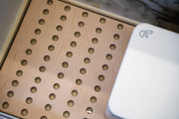 Campervan shower duckboard detail with perforated timber surface and clean, minimalist finish.