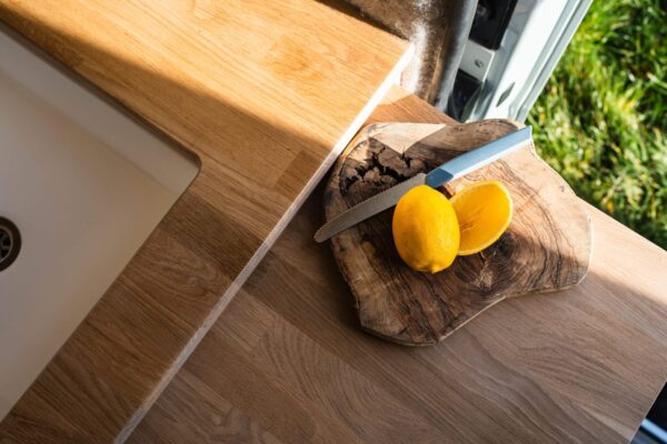 Close-up of campervan wooden worktop with chopping board, lemons and natural textures.