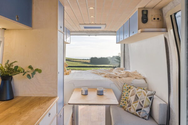 Rear lounge view of campervan with slatted timber ceiling and built-in cabinetry.