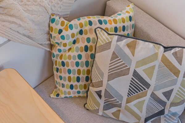 Campervan seating area with patterned cushions and soft textiles in muted tones.