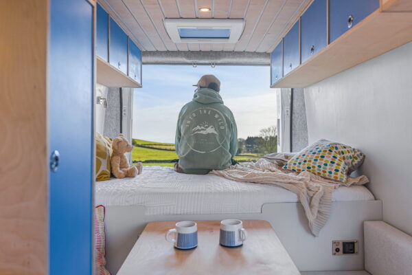 Campervan interior detail showing neutral fabric cushion with remote control.