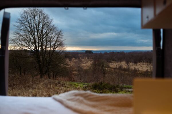 View from the rear bed of a Bhode campervan looking out across countryside landscape