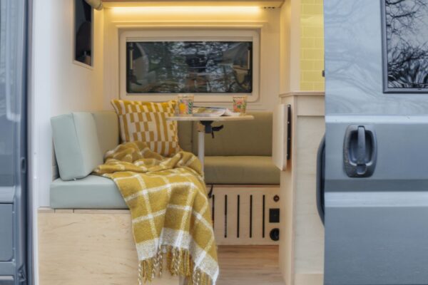 Cosy rear seating area inside a Bhode campervan with window view and Scandinavian-inspired upholstery