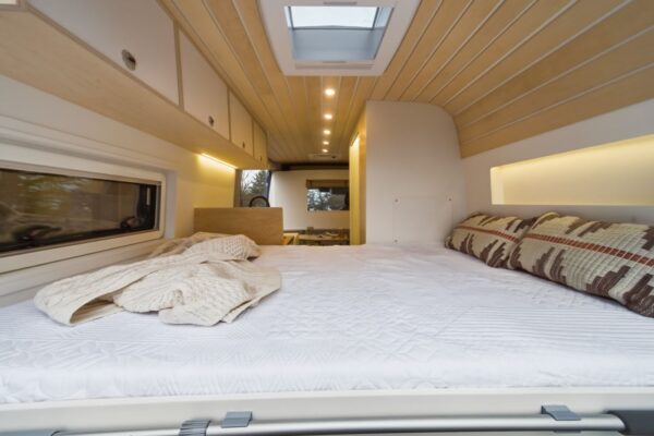 Fixed rear bed inside a Bhode campervan conversion with skylight and soft interior lighting