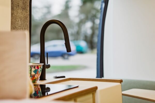 Kitchen sink and oak worktop inside a Bhode campervan conversion with countryside view through the window