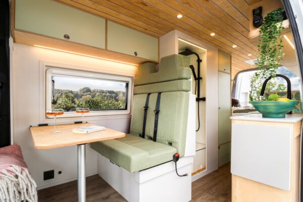 Campervan lounge seating and dining area with panoramic countryside views
