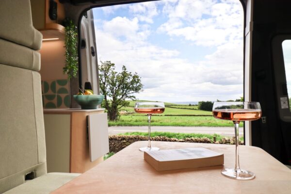 Campervan rear doors framing countryside views from the fixed bed area