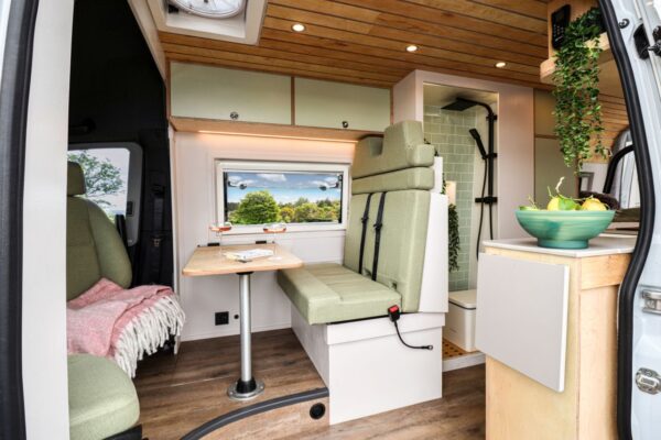 Bespoke campervan interior with lounge seating, shower room and dining table
