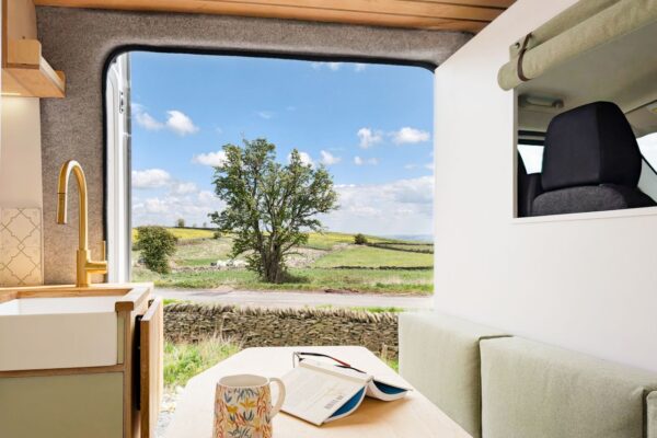 Campervan dining area with countryside views through the open side loading door