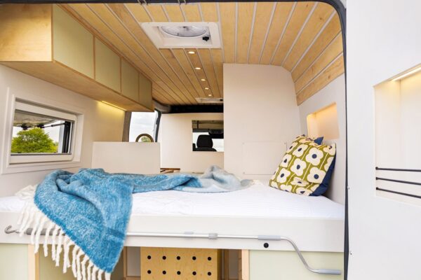 Fixed rear double bed with overhead storage in a bespoke campervan conversion