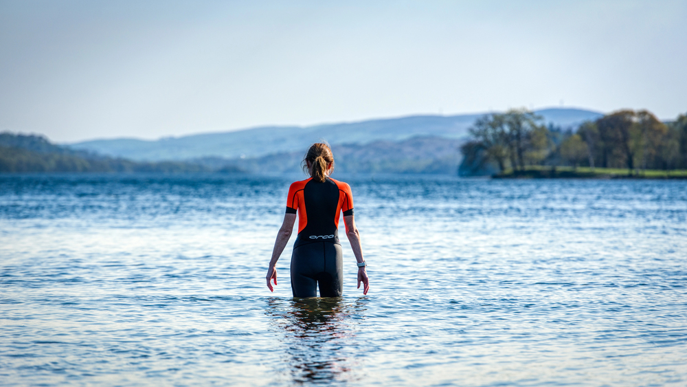 Woman wild swimming in a calm mountain lake